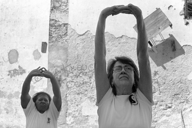 Black and white image of two women stretching their arms overhead. 